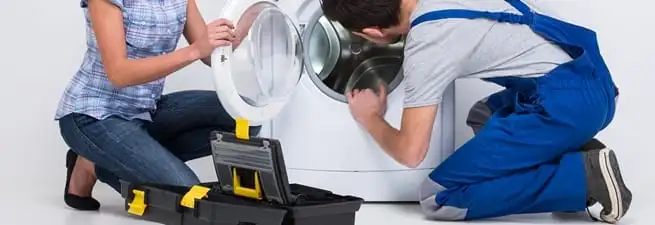 Washer repair technician inspecting a front-load washing machine with tools in Tampa, FL