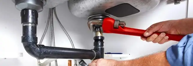 Garbage disposal repair technician tightening the sink drain and disposal connection in Tampa, FL