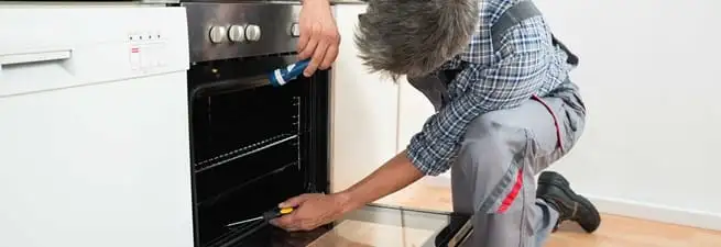 Oven repair technician inspecting and servicing an electric oven in Tampa, FL