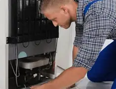 Refrigerator repair technician servicing the compressor and condenser area in Tampa, FL