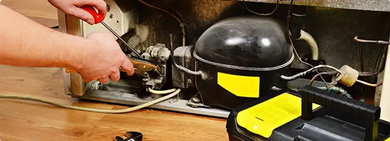 Refrigerator repair technician fixing the compressor and wiring in Tampa, FL