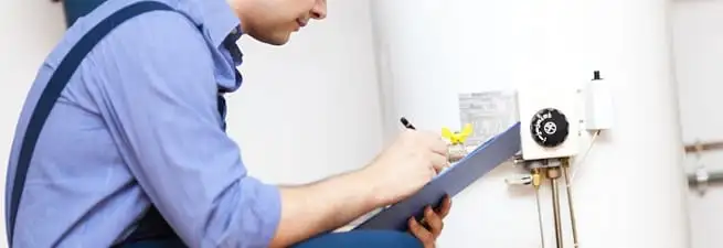 Water heater repair technician inspecting the unit and recording service notes in Tampa, FL
